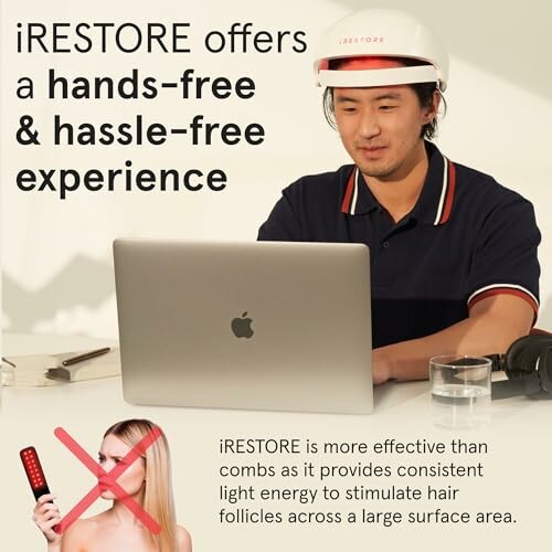 Man using iRestore device for hair growth while working on a laptop.