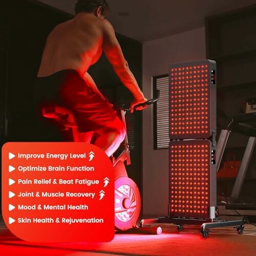 Person using stationary bike with red light therapy panels nearby.
